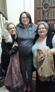 Three women standing next to each other at a soup kitchen