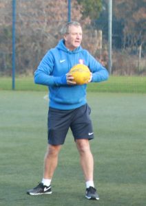 This is a photo of Hampshire FA Coach Michael Conway holding a football on an artificial grass pitch.