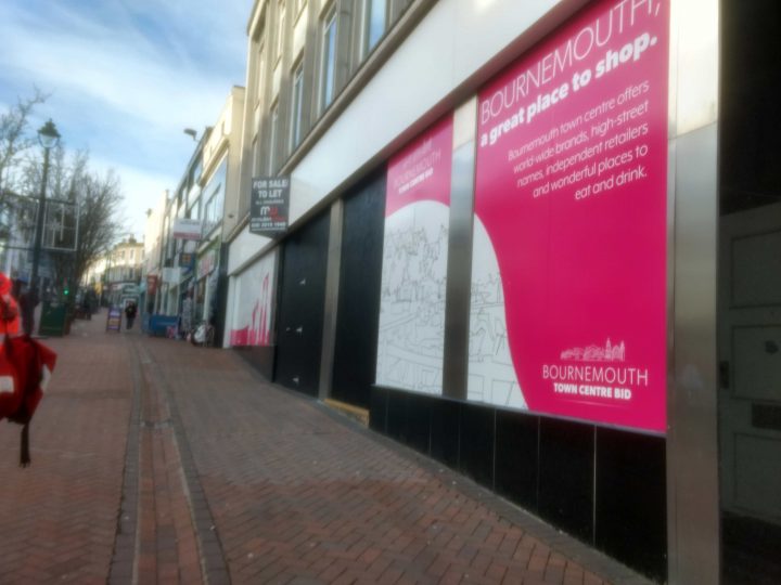 A poster saying 'Bournemouth - A great place to shop' sits next to a To Let sign.