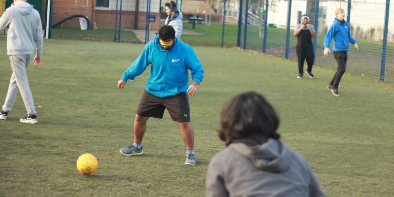 This is an action shot of some Bournemouth University students playing blind football at a taster session.