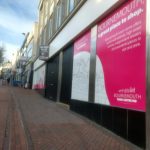 A poster saying 'Bournemouth - A great place to shop' next to a to let sign.