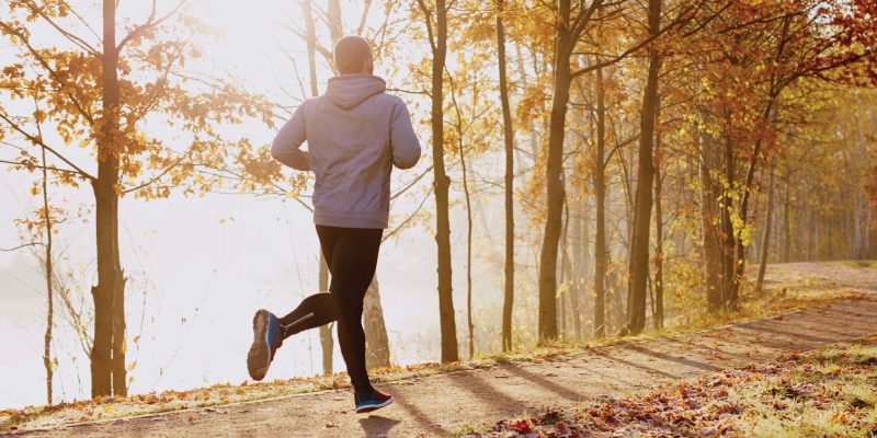 Photo of a man running along side a lake