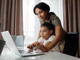 A mother and a child looking at a laptop screen together.