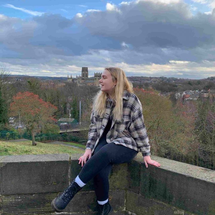 Jen sat on a wall with York landscape in the background