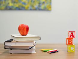 Picture of a child's homeschooling set with an apple on a pile of books, a pile of pens, and ABC blocks on a table