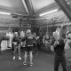 Action shot at West Kingsdown Boxing Club, coaches engage in one on one pad practice with some individuals, while the rest of the group work with the boxing bags behind.