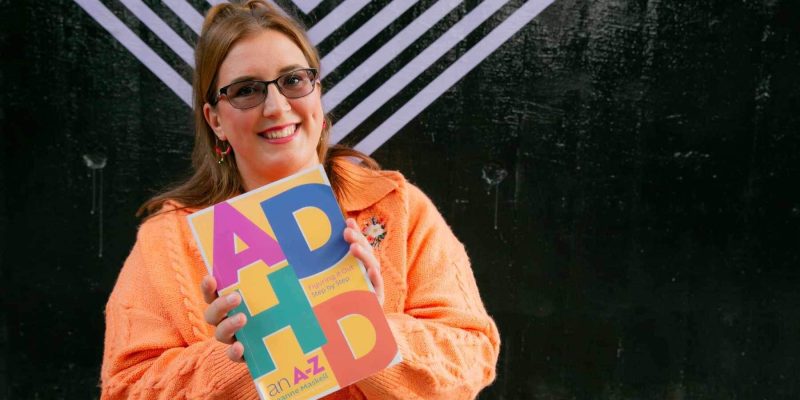 Rachel Clayton, owner of Fruition For Business, holding a book named ADHD.
