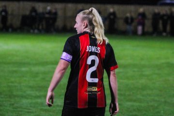 Abby Jones wearing the captains armband with her back to the camera so you can see 'Jones 2' on the back of her shirt.