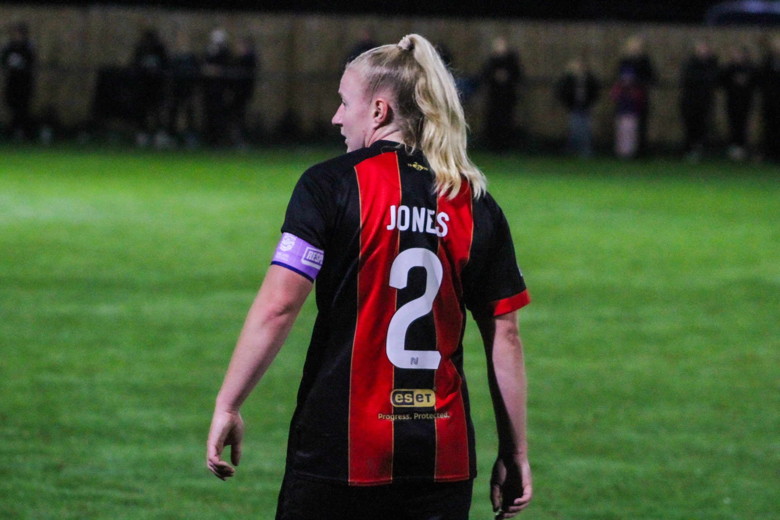 Abby Jones wearing the captains armband with her back to the camera so you can see 'Jones 2' on the back of her shirt.