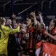 The Bournemouth team celebrate winning the Hampshire FA Cup. Maisy Smith is front and centre holding the trophy. The team is jumping up and down.