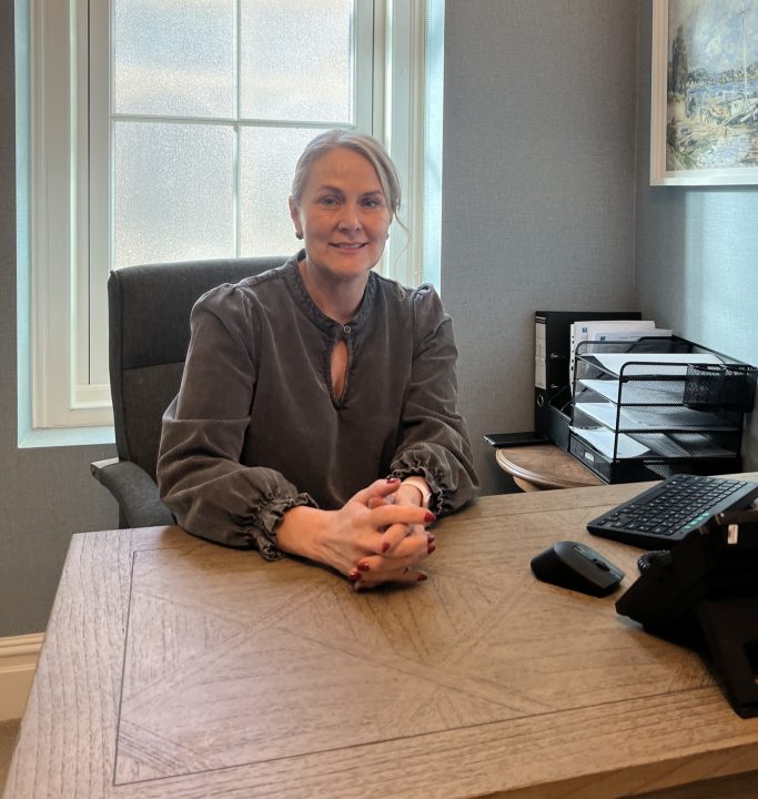 kim harding general manager sitting at desk smiling