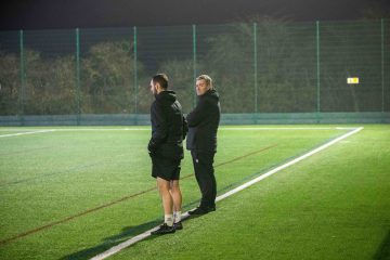 Manager Steve Cuss stood next to one of his coaching staff overseeing a training session. 