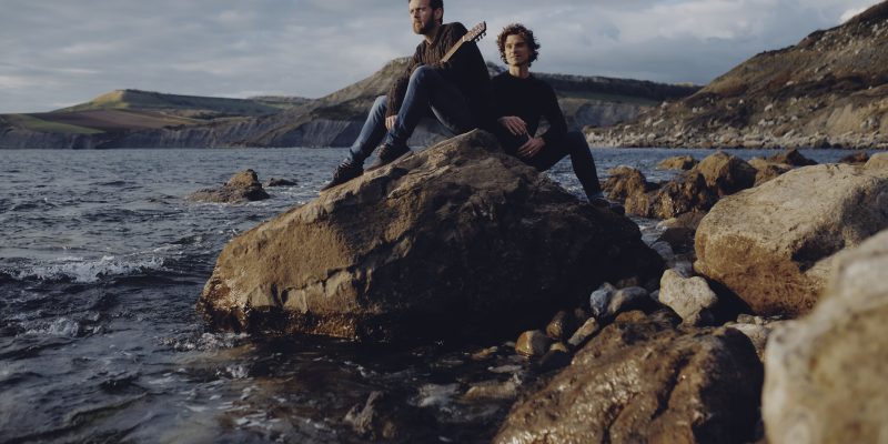 Two men sit on a rock