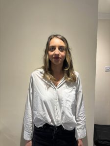 image of a women with brown hair in a white shirt and black trousers