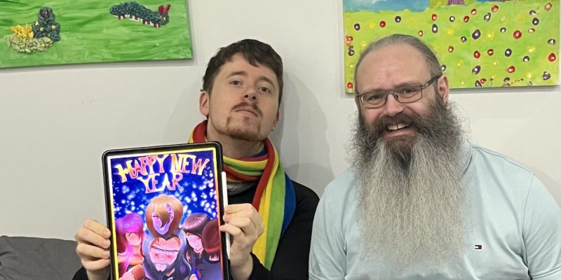 two people sitting on a sofa showing off some art