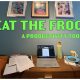 a cluttered desk with picture frames hanging on a blue wall, words 'EAT THE FROG: A productivity tool' written over the image in green.