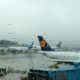 Plane in an airport gate with rain on the window and grey skies.