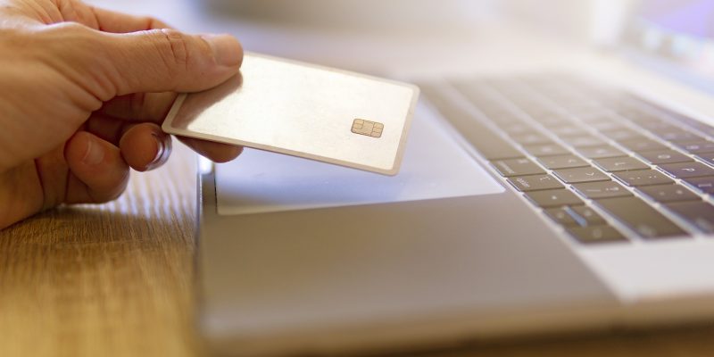 Person on laptop holding debit card