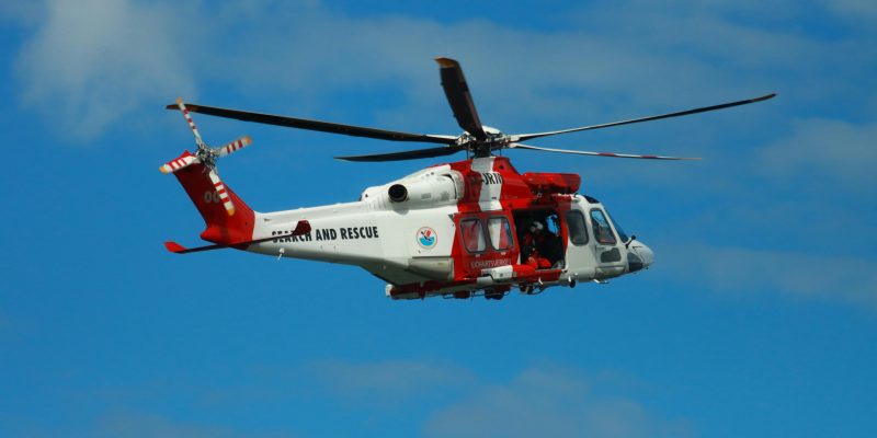White and Red helicopter flying in a clear blue sky