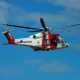 White and Red helicopter flying in a clear blue sky